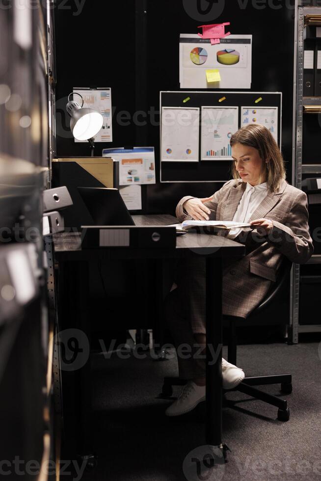 policía oficial analizando crimen escena archivos, trabajando tiempo extraordinario a delincuente caso en archivar habitación. privado detective descubriendo nuevo pistas acerca de misterioso sospechar. criminología Departamento concepto foto