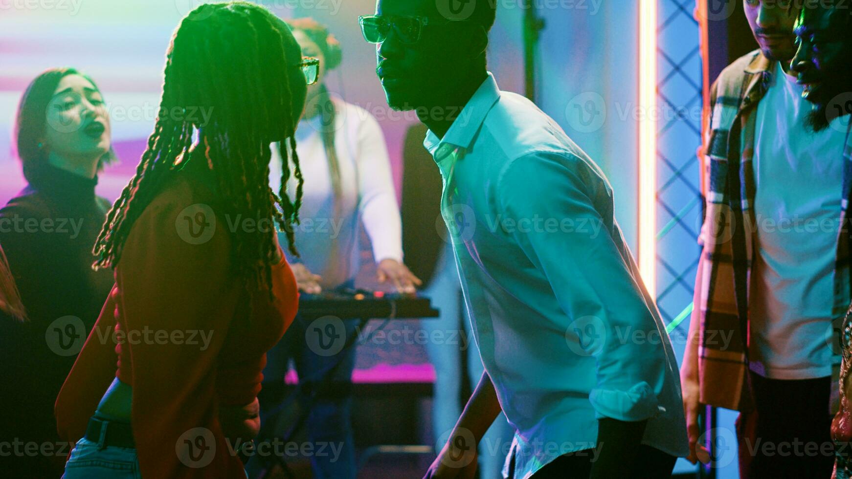 Diverse people having fun at party, dancing and jumping together at nightclub. Crowd of adults preparing to start breakdance battle to show off disco moves on dance floor. Handheld shot. photo