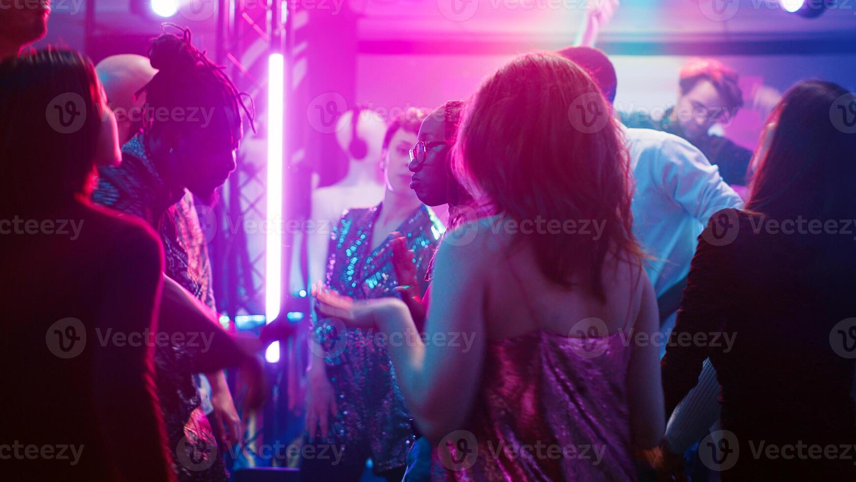 Cheerful persons doing dance moves at party, dancing together and having fun on modern funky music. Multiethnic group of people enjoying performance show on dance floor. Tripod shot. photo