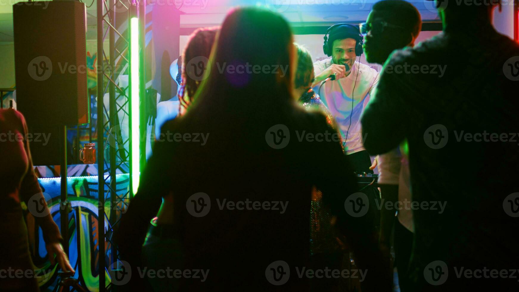 Young people having fun at nightclub doing dance moves on electronic music, enjoying social gathering disco party. Friends dancing together at club, feeling cheerful at discotheque. Handheld shot. photo