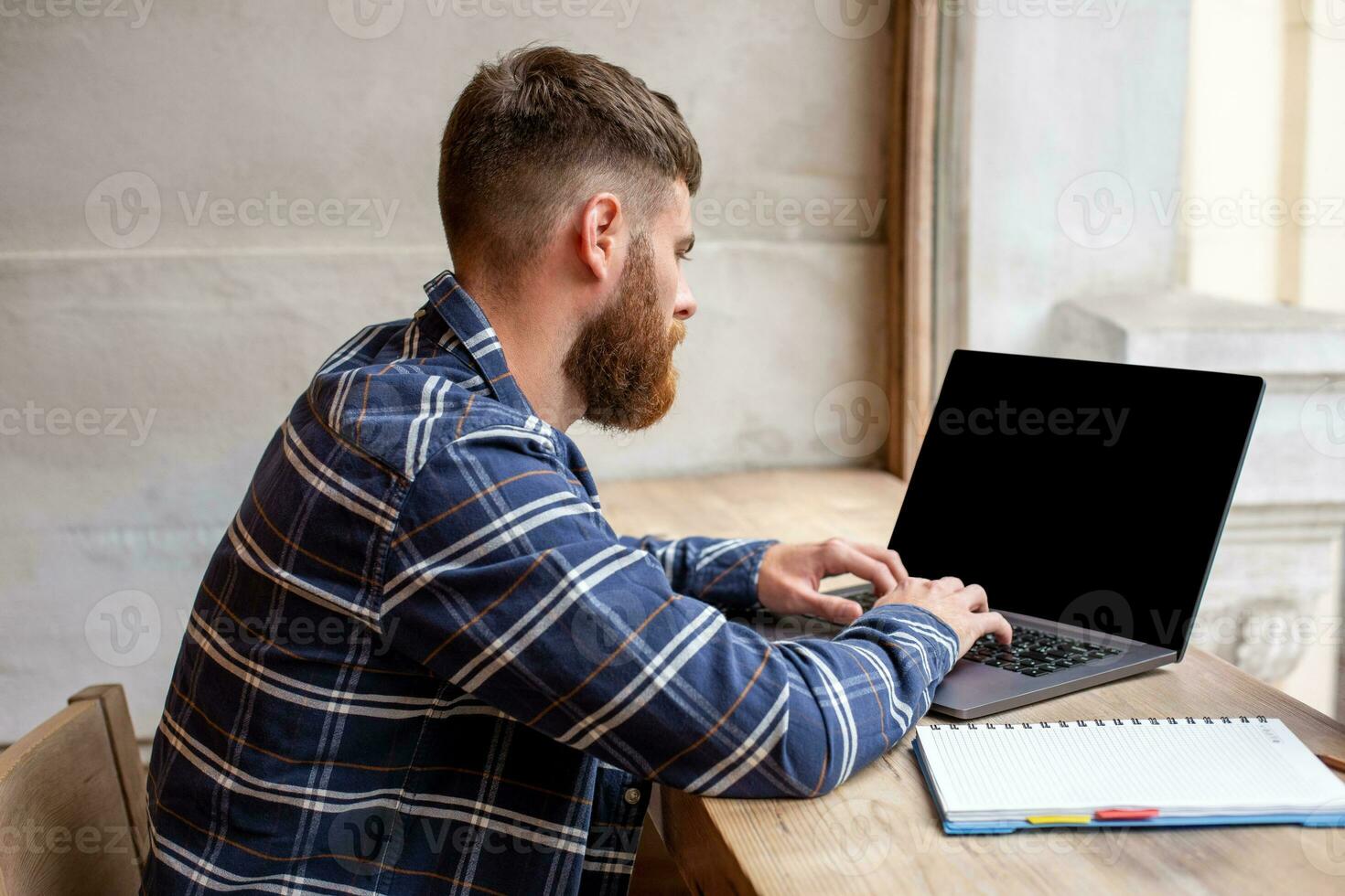 Young man chatting via net-book during work break in coffee shop, male sitting in front open laptop computer with blank copy space screen. photo