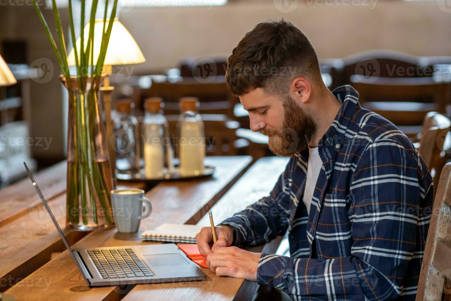 Casual business man or freelancer planning his work on notebook, working on laptop computer with smart phone, cup of coffee on table at coffee shop or home office. photo