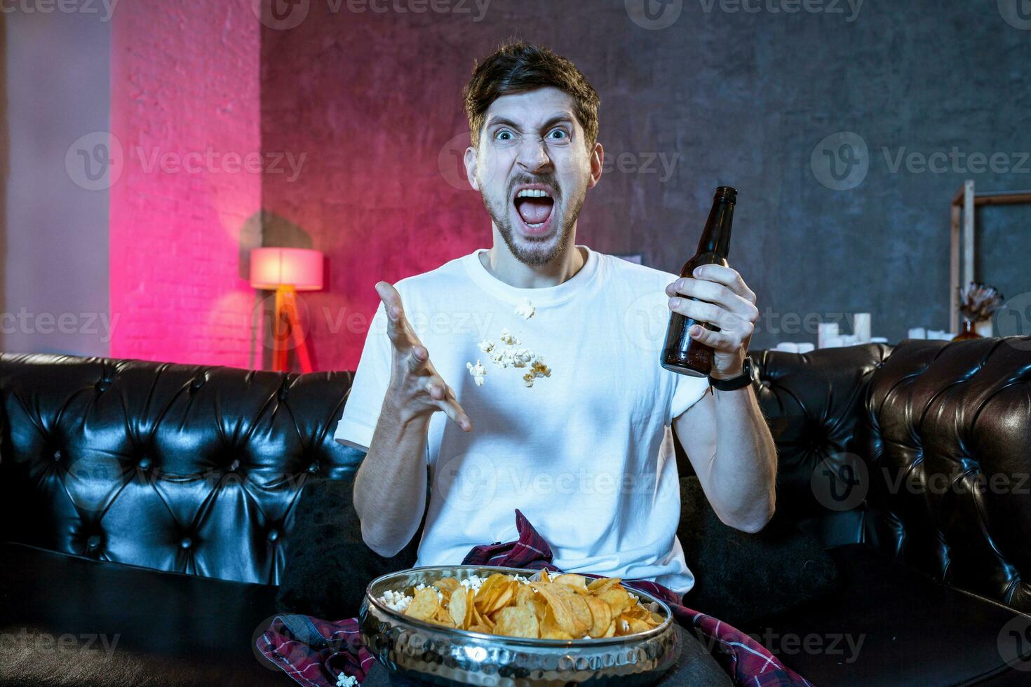 Young supporter man watching football game on television sitting photo