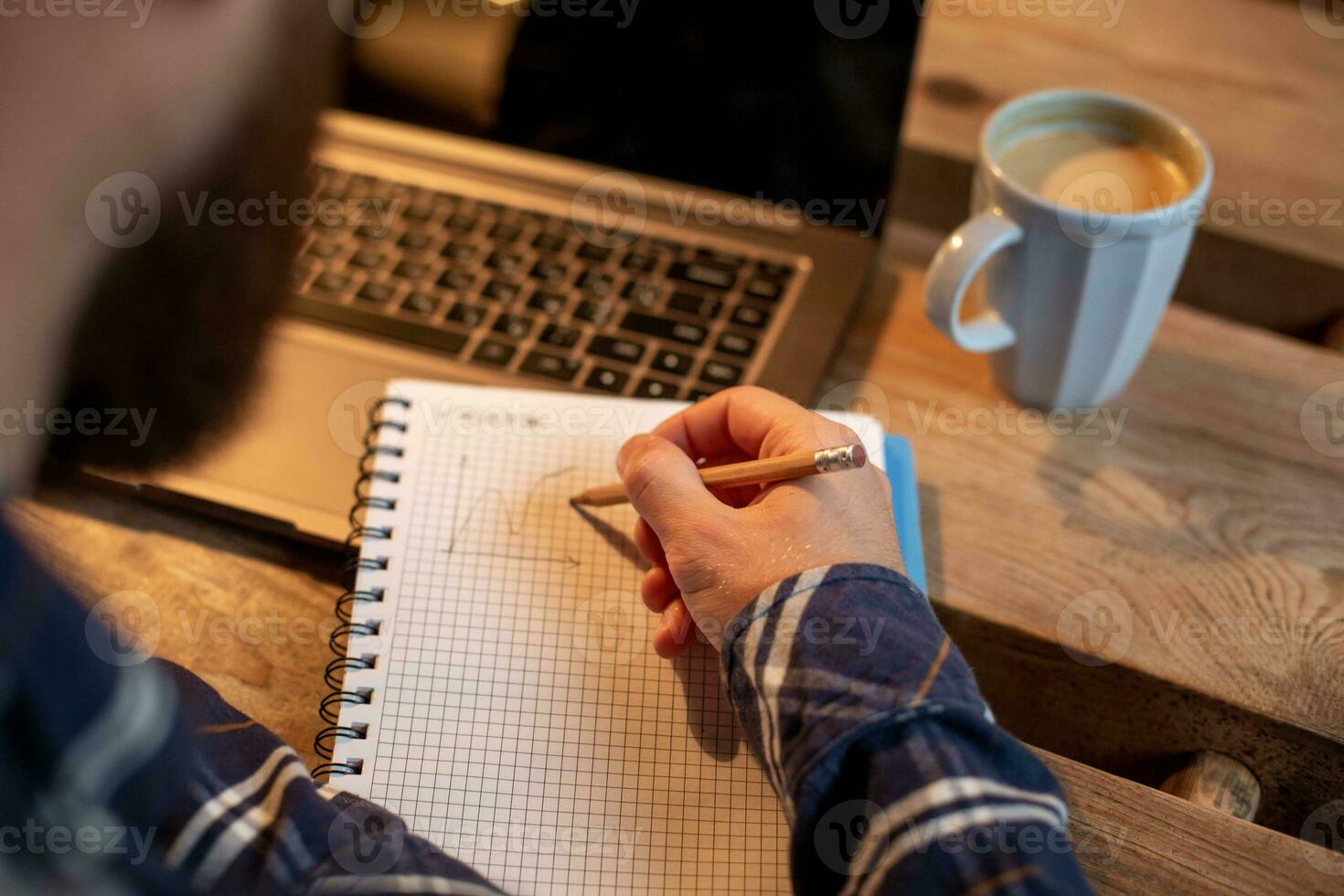 Cropped image of casual business man or freelancer planning his work on notebook, working on laptop computer with smart phone, cup of coffee on table at coffee shop or home office. photo