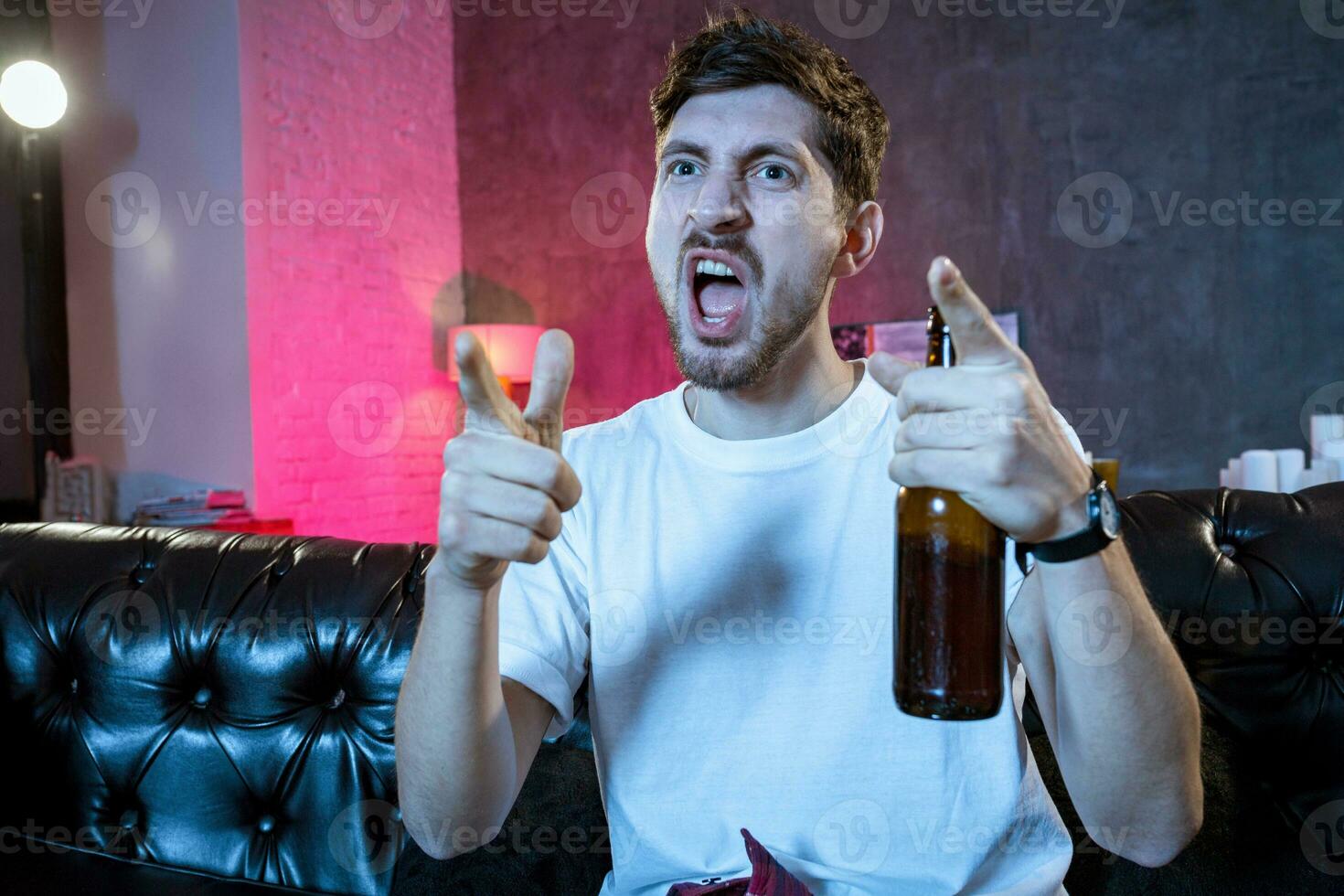 Young supporter man watching football game on television sitting photo