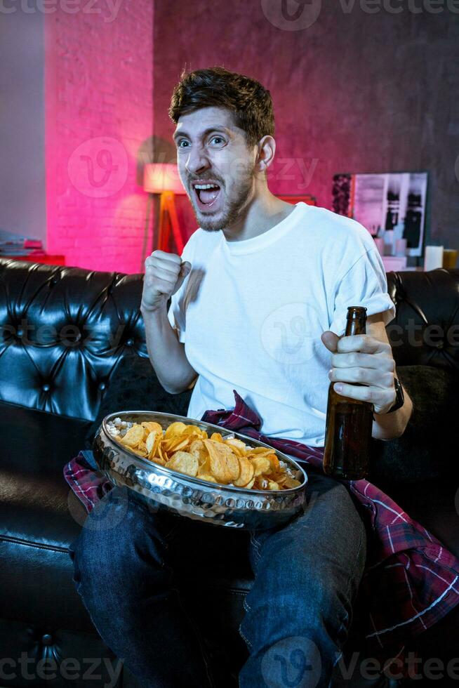 Young fan man watching football game on television celebrating g photo