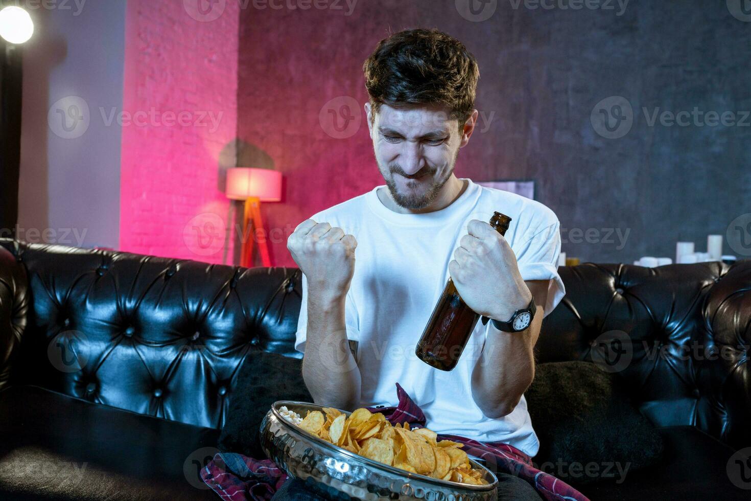 Young man watching football game on television, celebrating goal photo