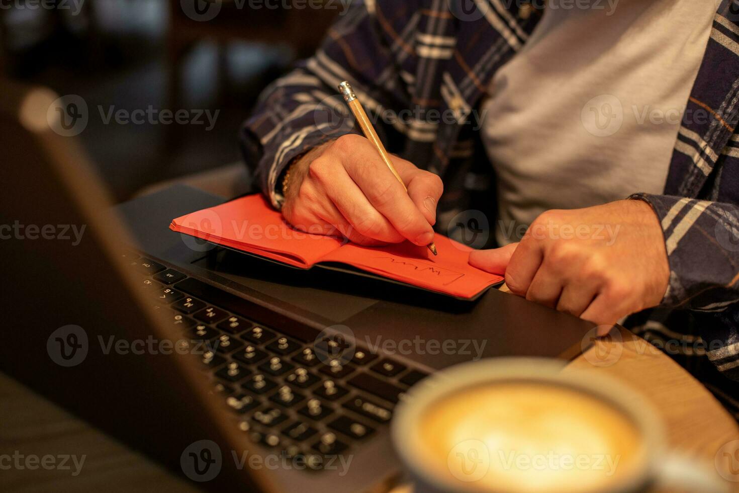 Cropped image of casual business man or freelancer planning his work on notebook, working on laptop computer with smart phone, cup of coffee on table at coffee shop or home office. photo