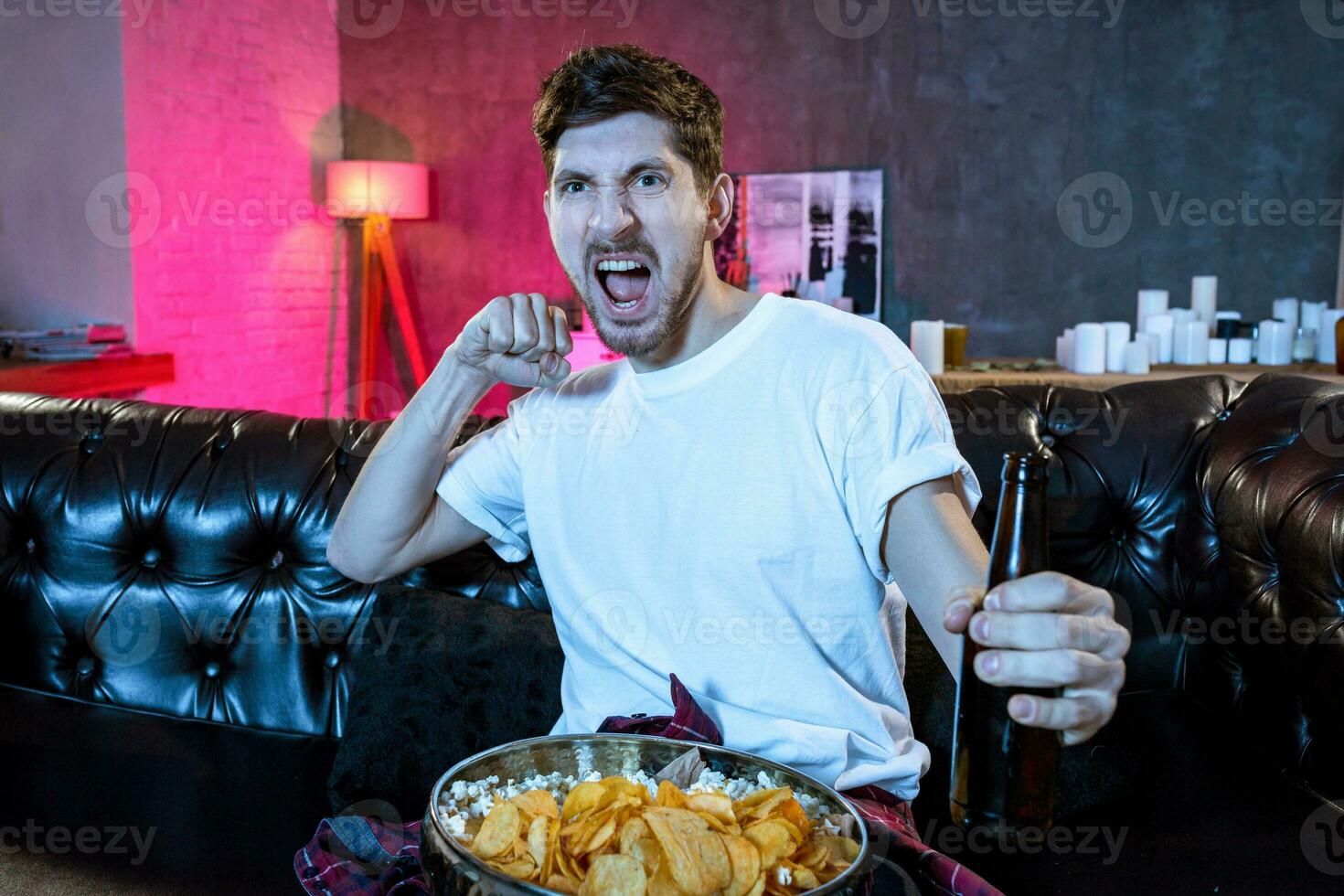 Young fan man watching football game on television celebrating g photo