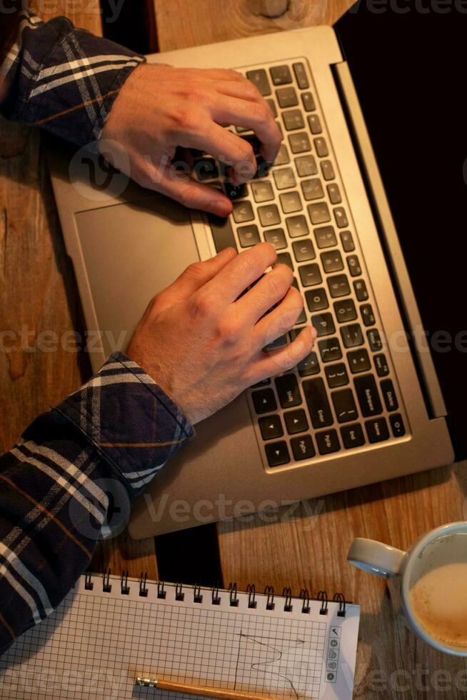 Young man drinking coffee in cafe and using laptop. Man's hands using laptop during coffee break photo