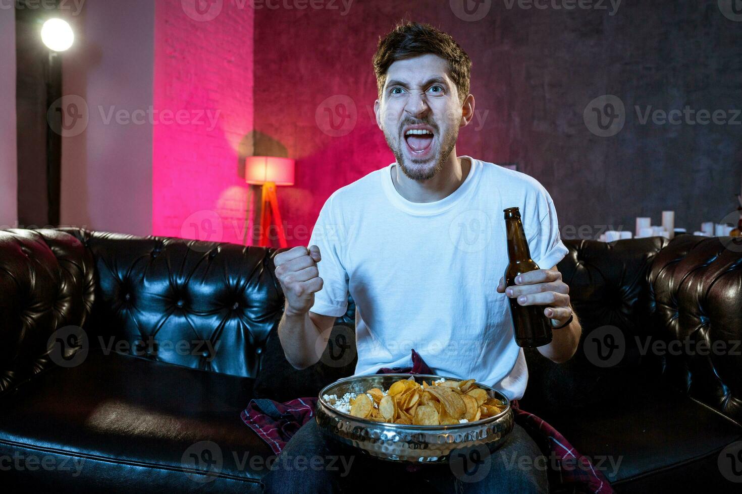 Young supporter man watching football game on television sitting photo