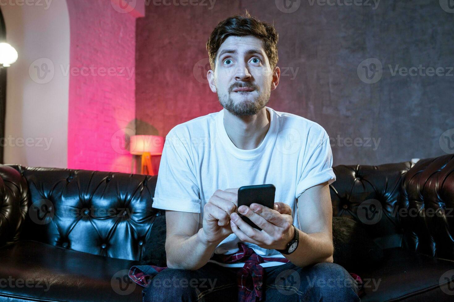 Young supporter man watching football game on television sitting photo