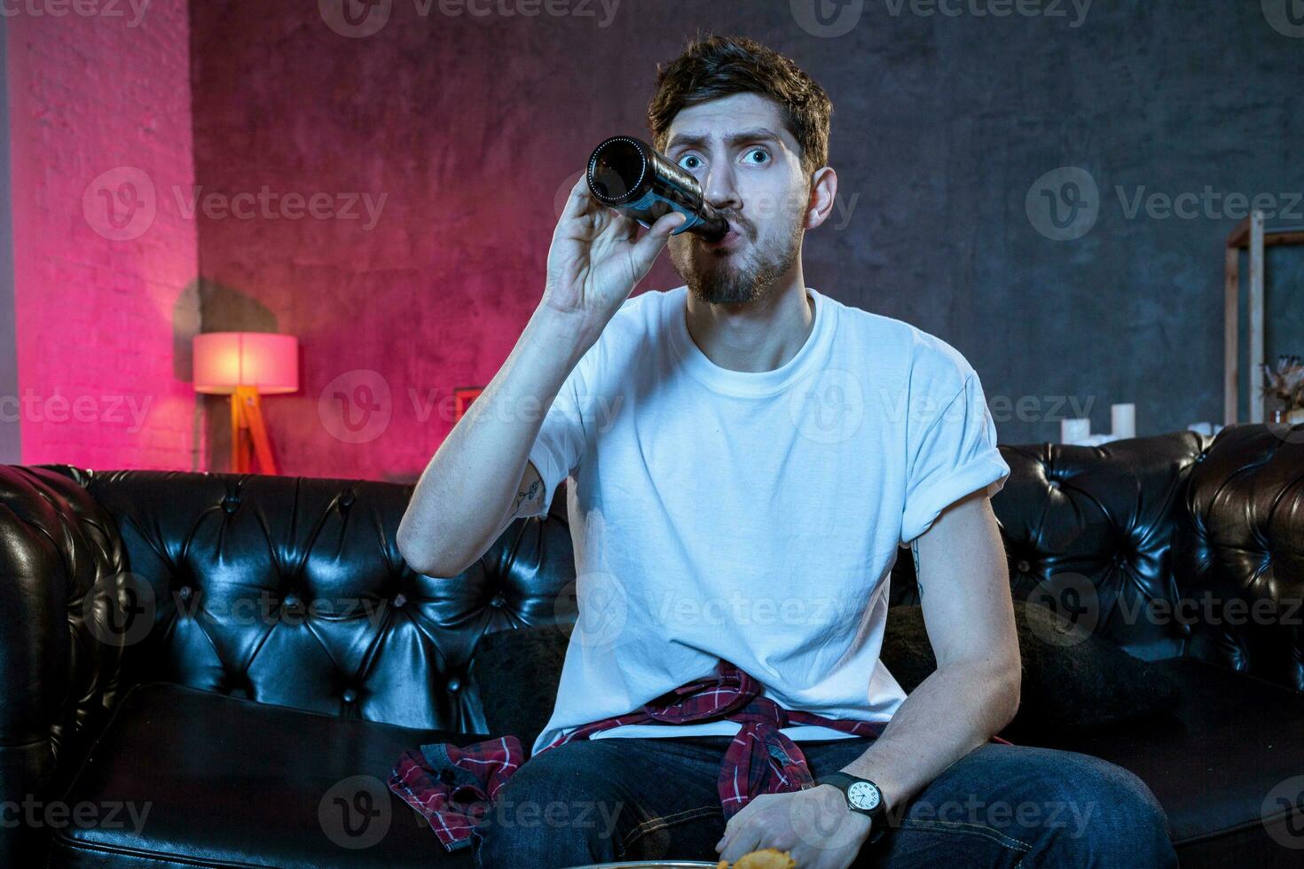Young supporter man watching football game on television sitting photo