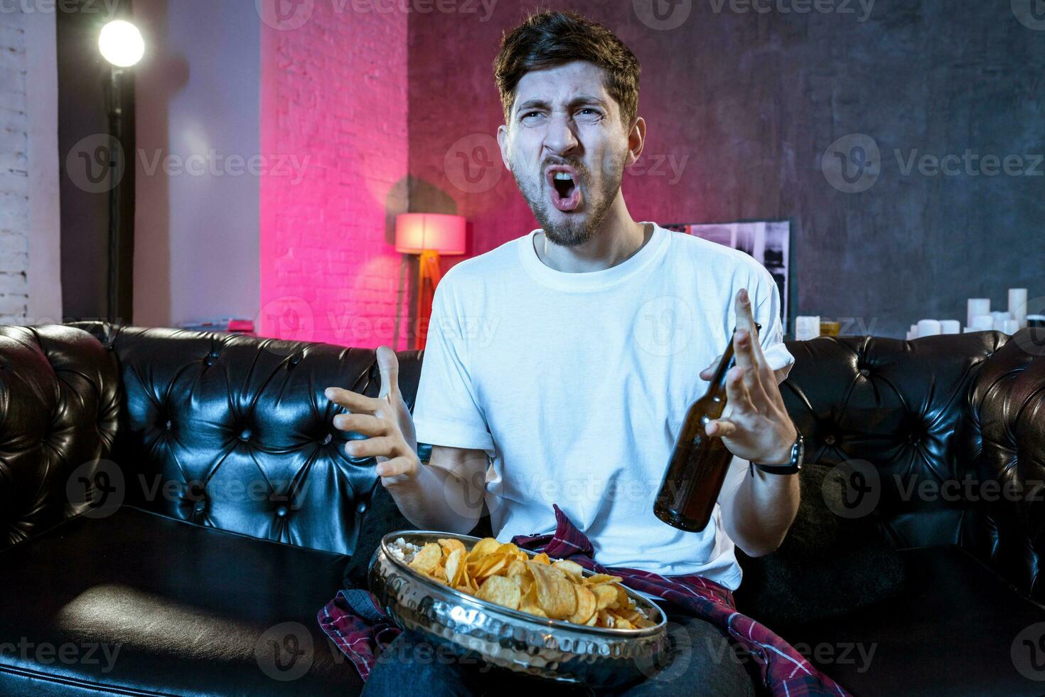 Young man watching football game on television, celebrating goal photo