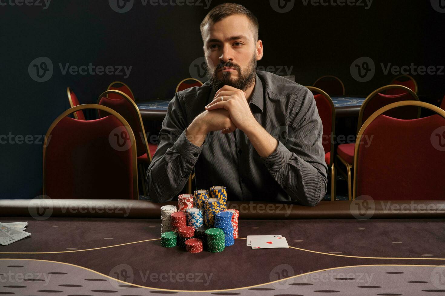 Handsome bearded man is playing poker sitting at the table in casino. photo