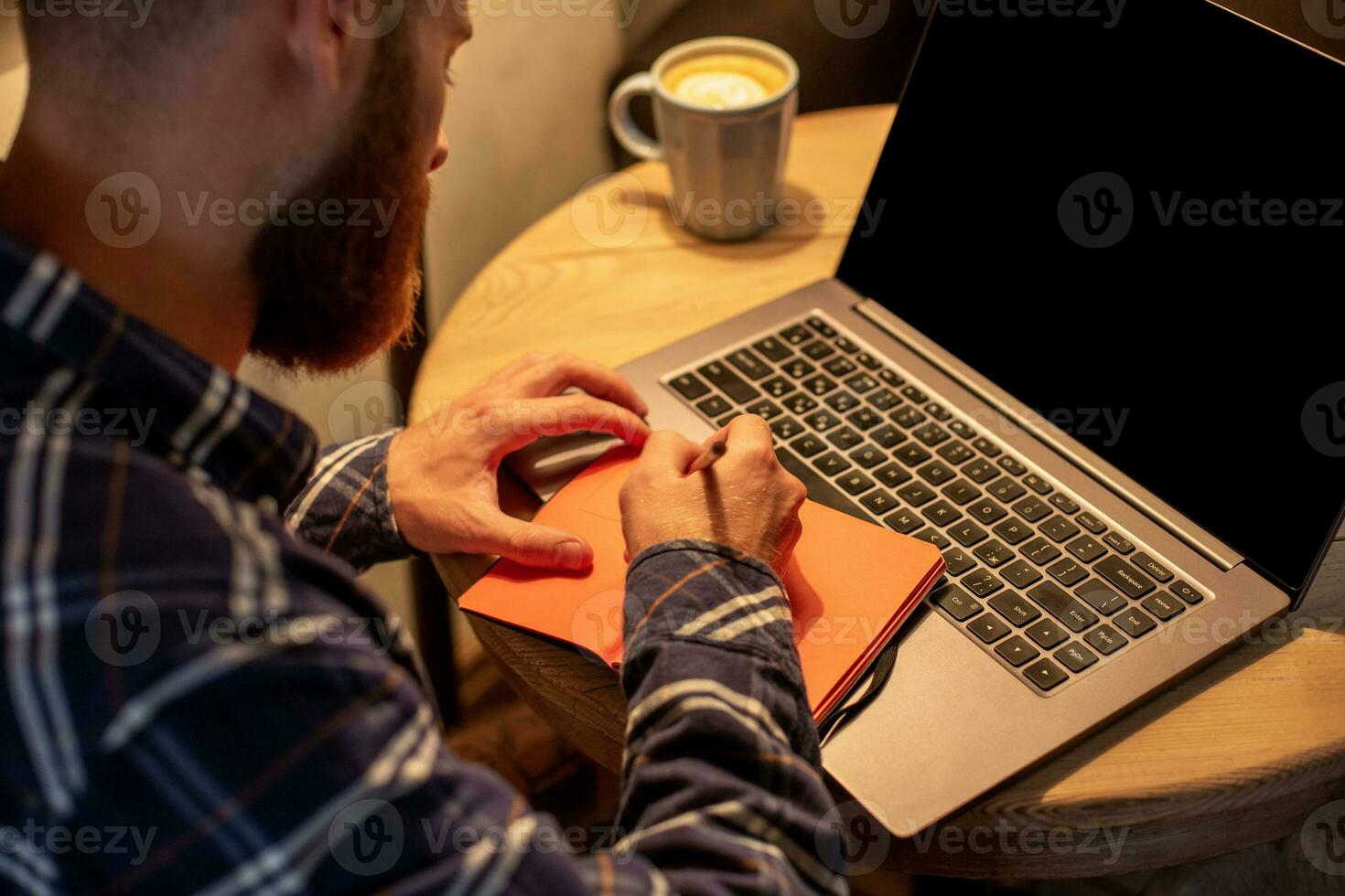 Cropped image of casual business man or freelancer planning his work on notebook, working on laptop computer with smart phone, cup of coffee on table at coffee shop or home office. photo