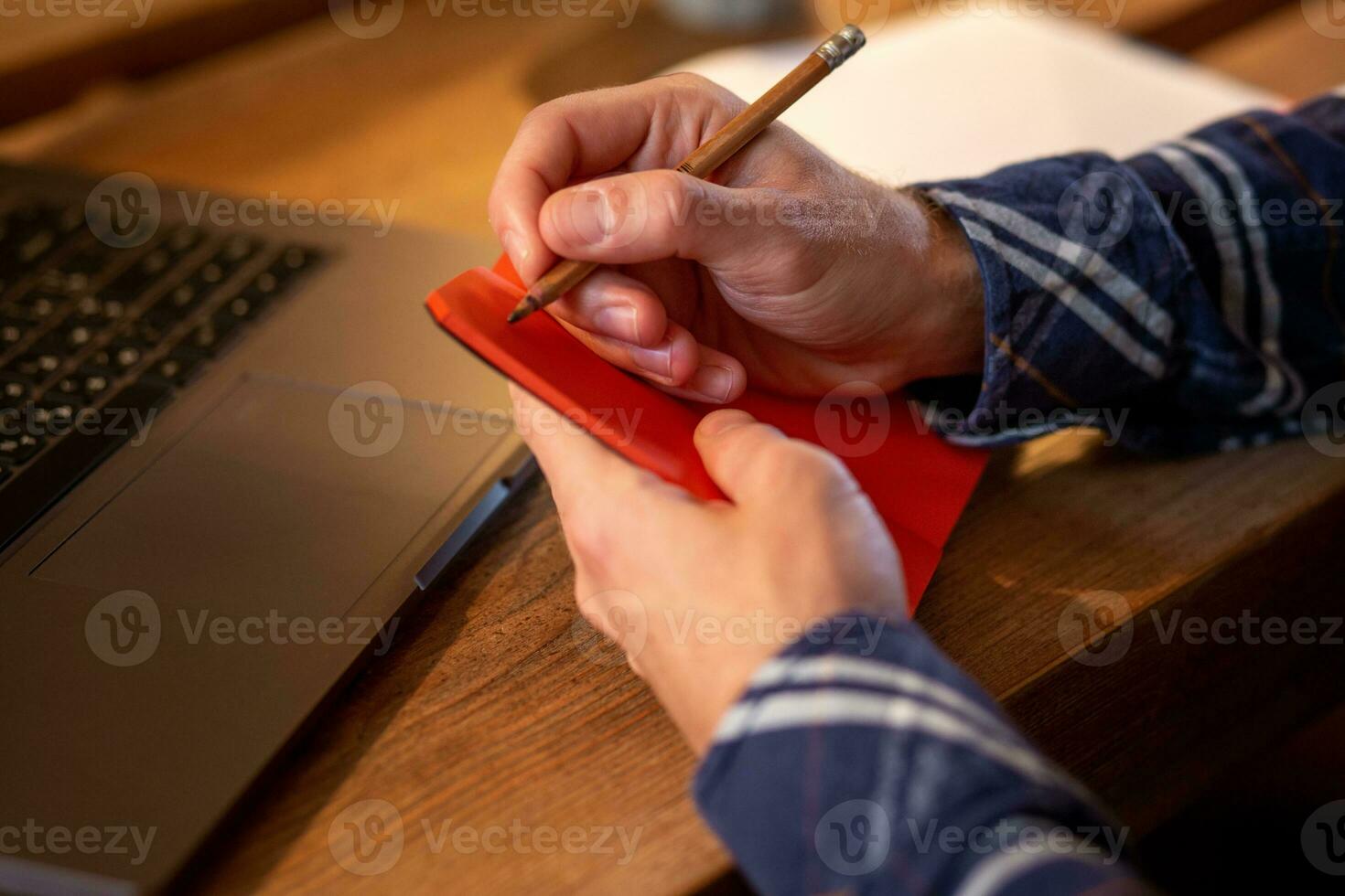 Cropped image of casual business man or freelancer planning his work on notebook, working on laptop computer with smart phone, cup of coffee on table at coffee shop or home office. photo