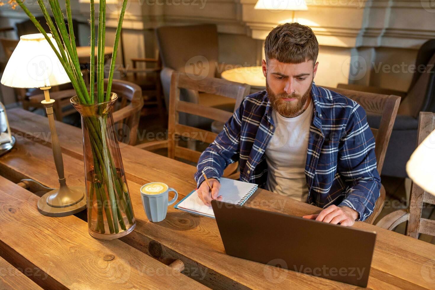 Casual business man or freelancer planning his work on notebook, working on laptop computer with smart phone, cup of coffee on table at coffee shop or home office. photo