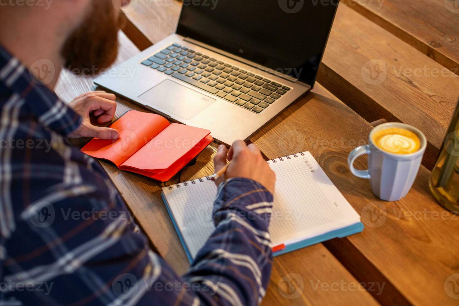 Cropped image of casual business man or freelancer planning his work on notebook, working on laptop computer with smart phone, cup of coffee on table at coffee shop or home office. photo