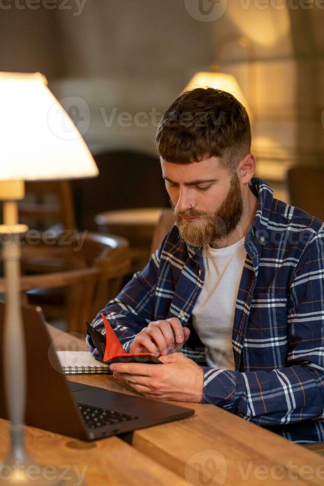 Casual business man or freelancer planning his work on notebook, working on laptop computer with smart phone, cup of coffee on table at coffee shop or home office. photo