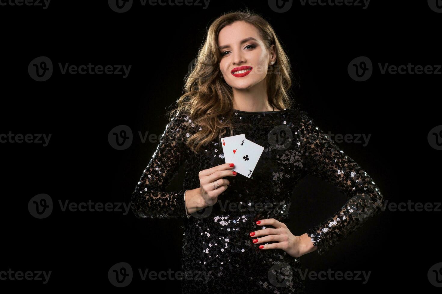 Young woman holding playing cards against a black background photo