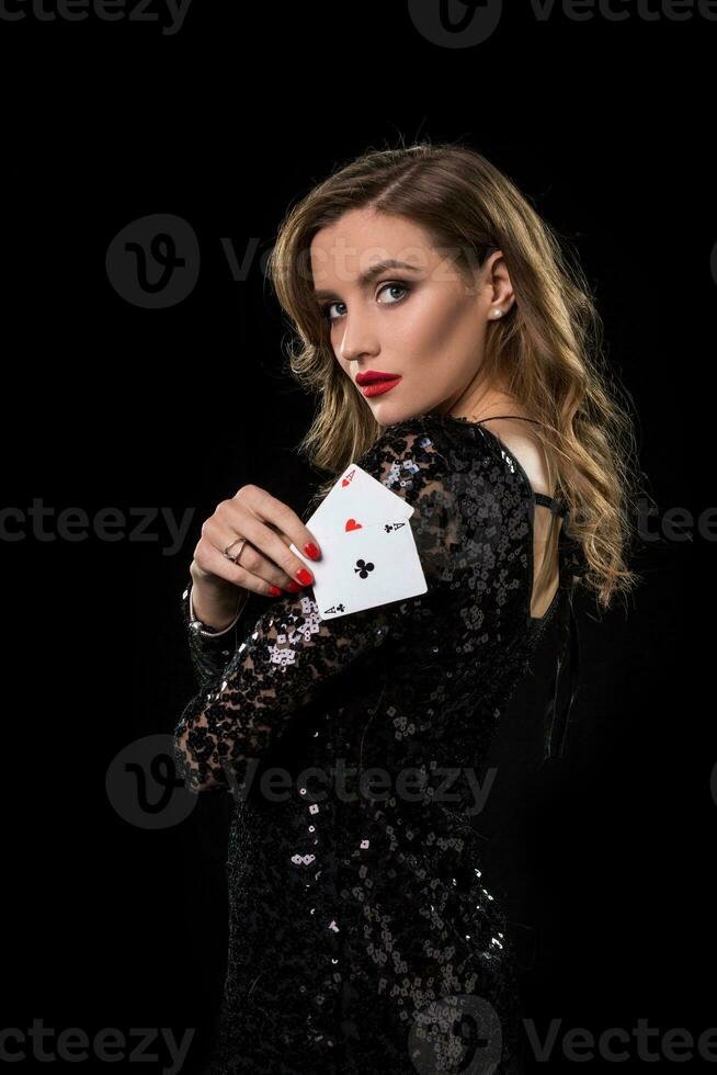 Young woman holding playing cards against a black background photo