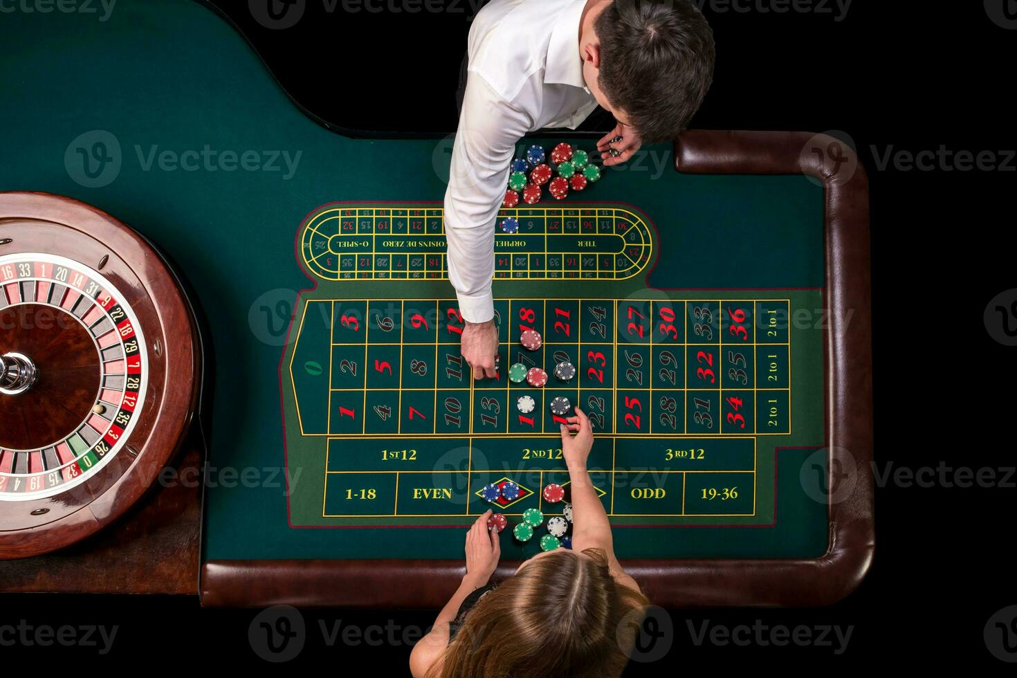 Man croupier and woman playing roulette at the table in the casino. Top view at a roulette green table with a tape measure. photo