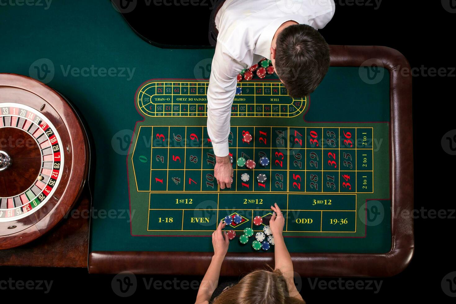 Man croupier and woman playing roulette at the table in the casino. Top view at a roulette green table with a tape measure. photo