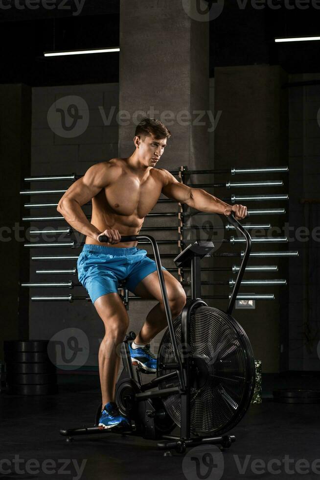 atleta hombre andar en bicicleta en el gimnasia. foto