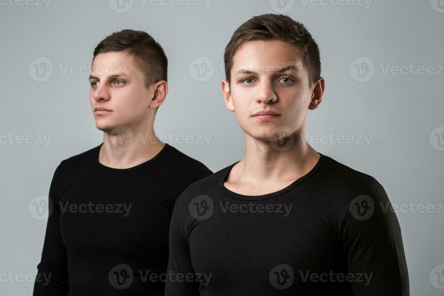 The two twin brother stand on the gray background photo