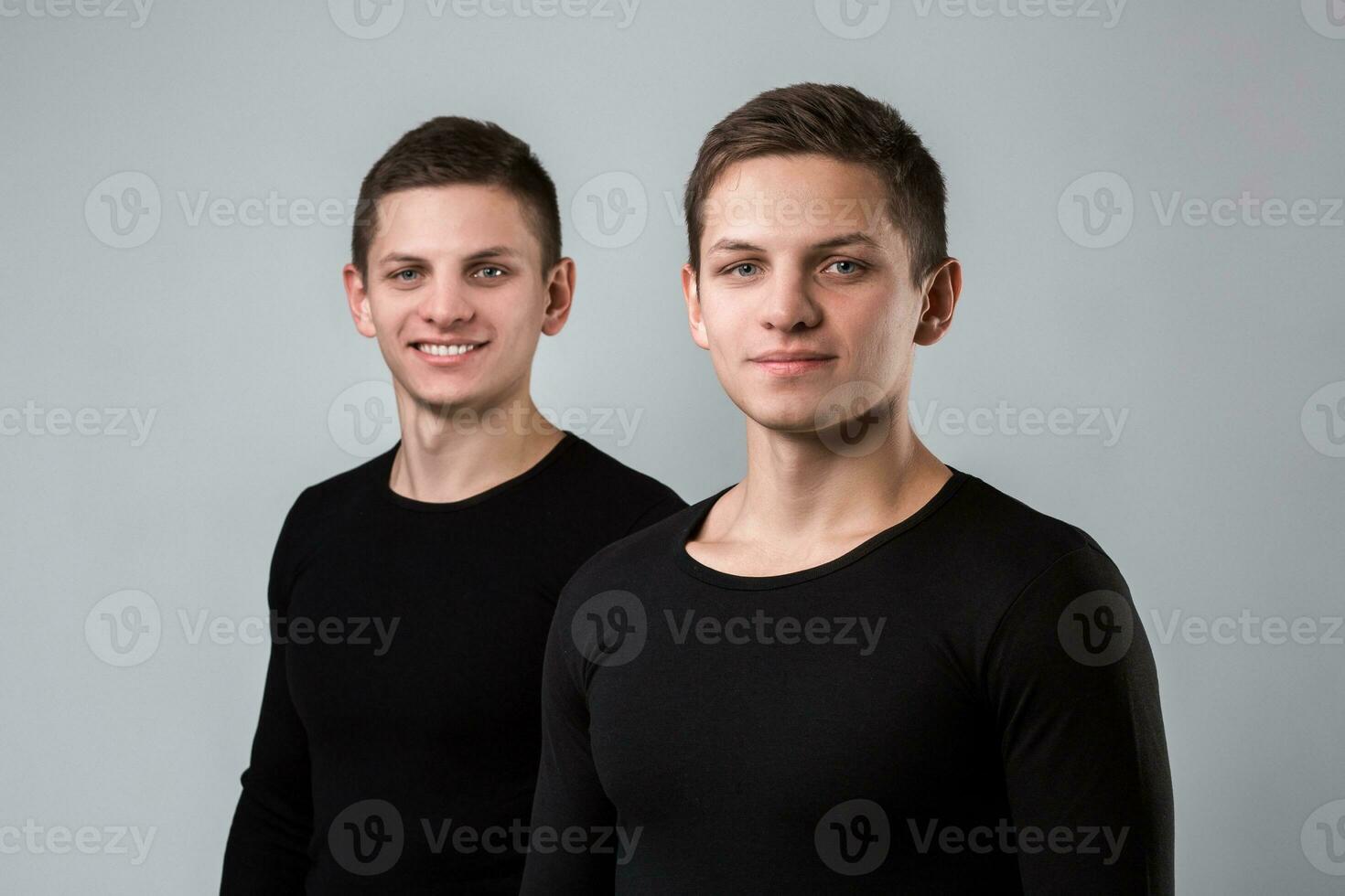 The two twin brother stand on the gray background photo