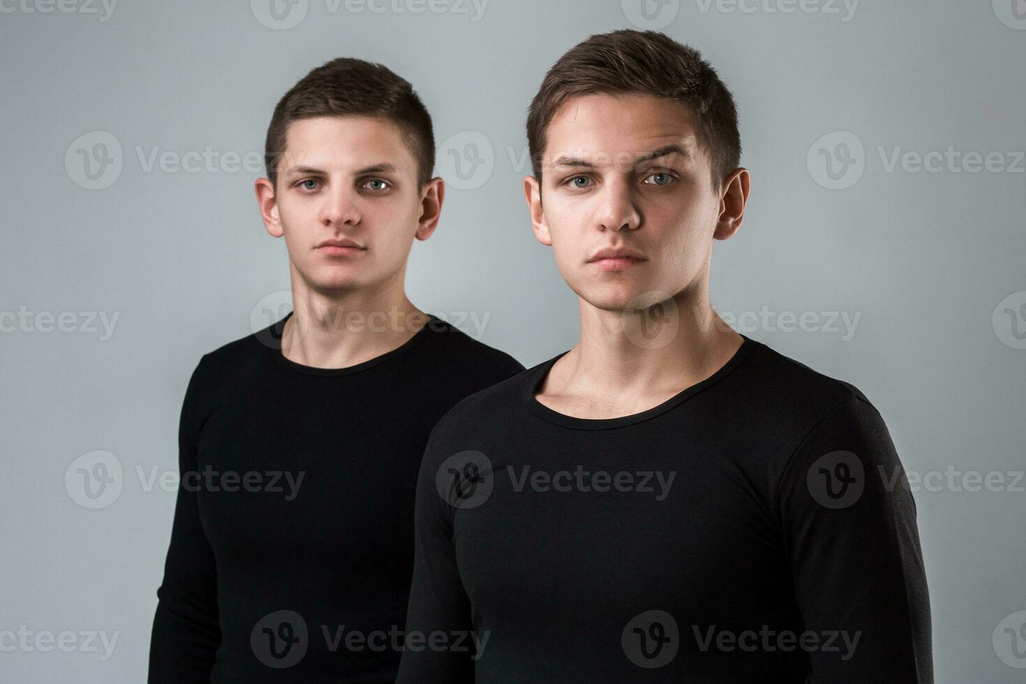 The two twin brother stand on the gray background photo