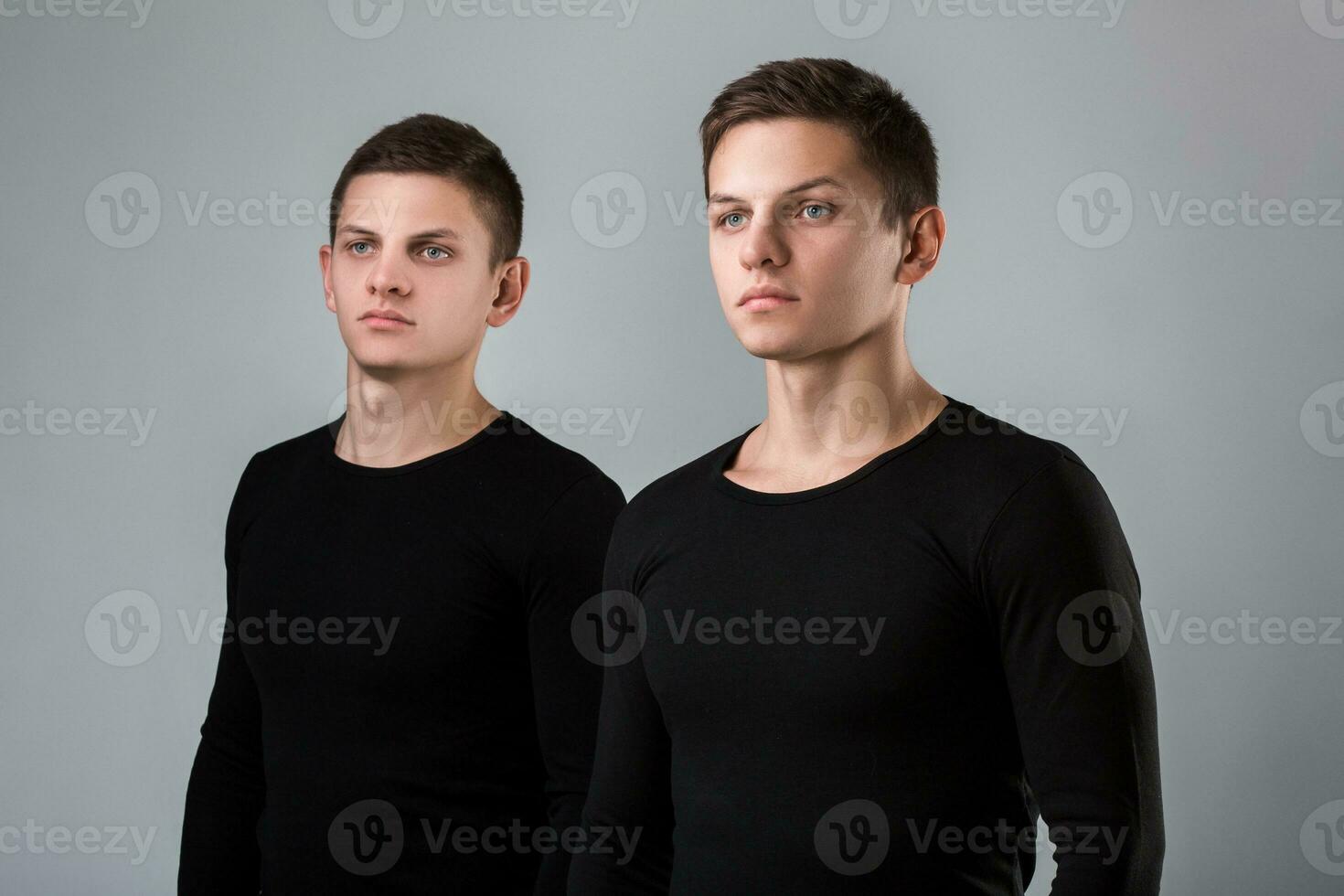 The two twin brother stand on the gray background photo