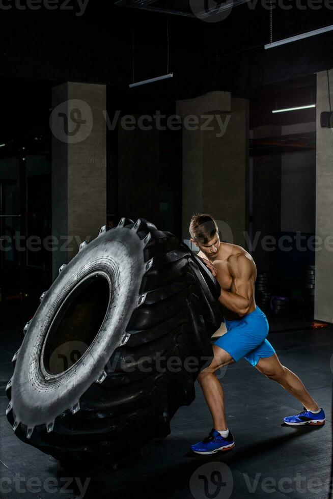 training - man flipping tire in gym photo