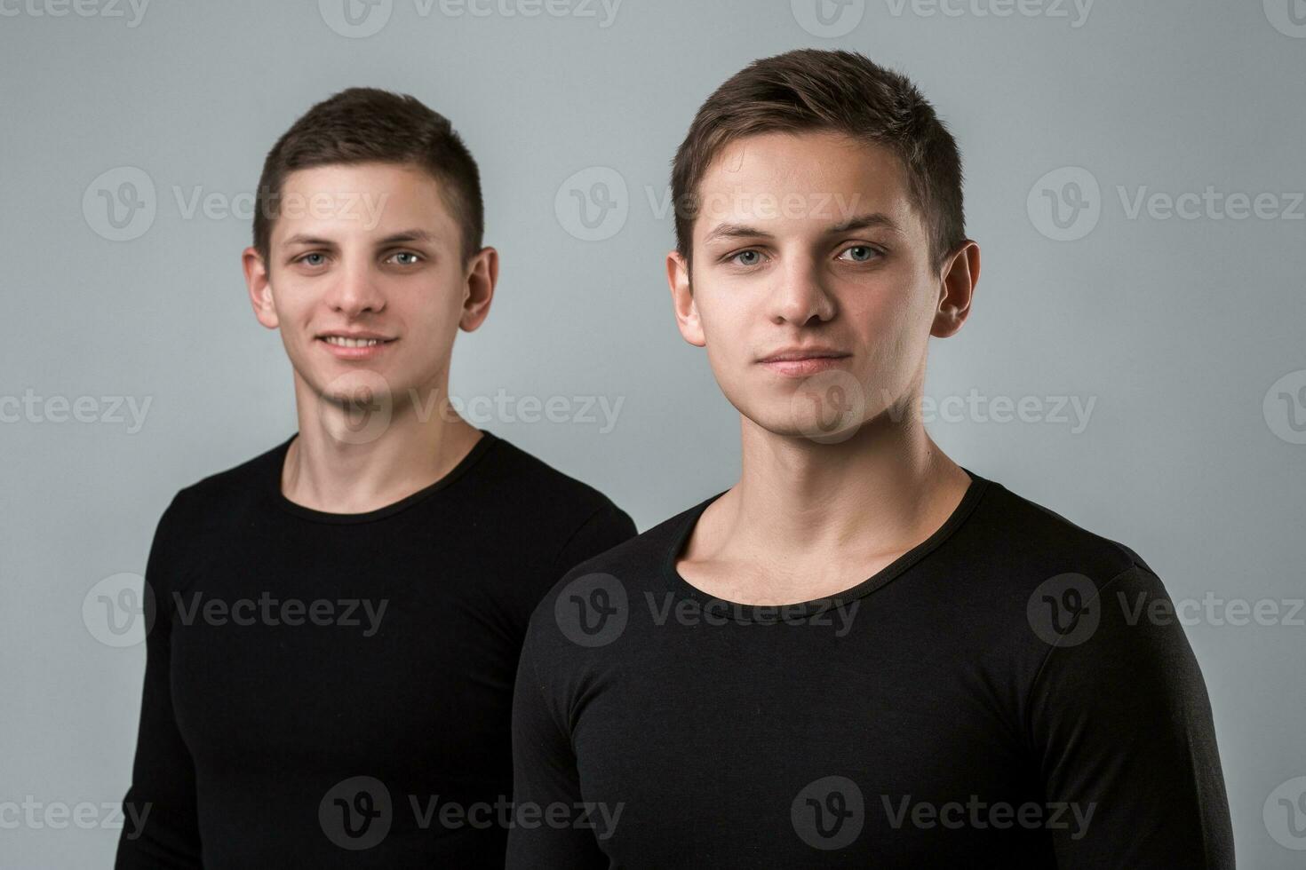 The two twin brother stand on the gray background photo