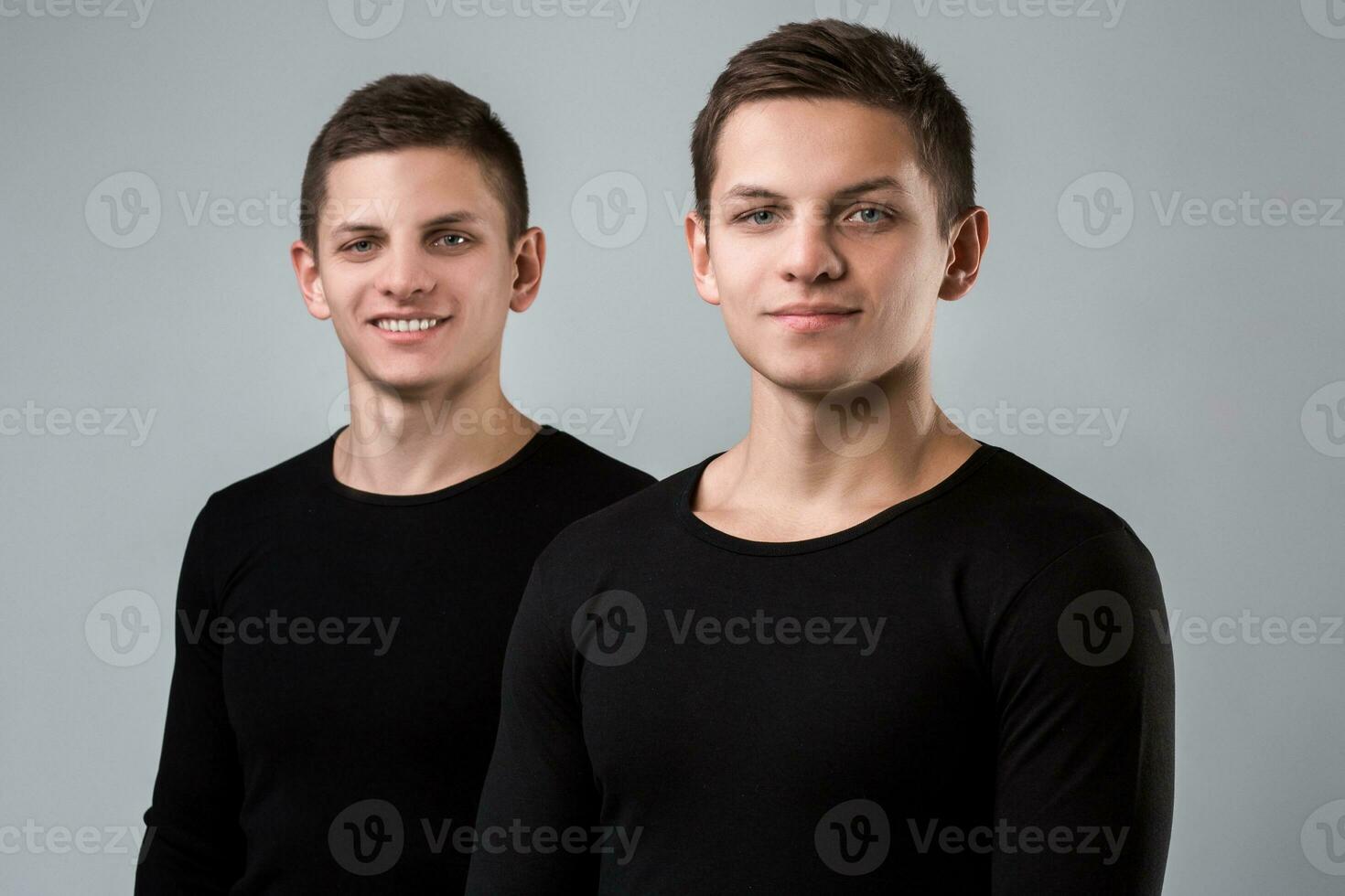 The two twin brother stand on the gray background photo