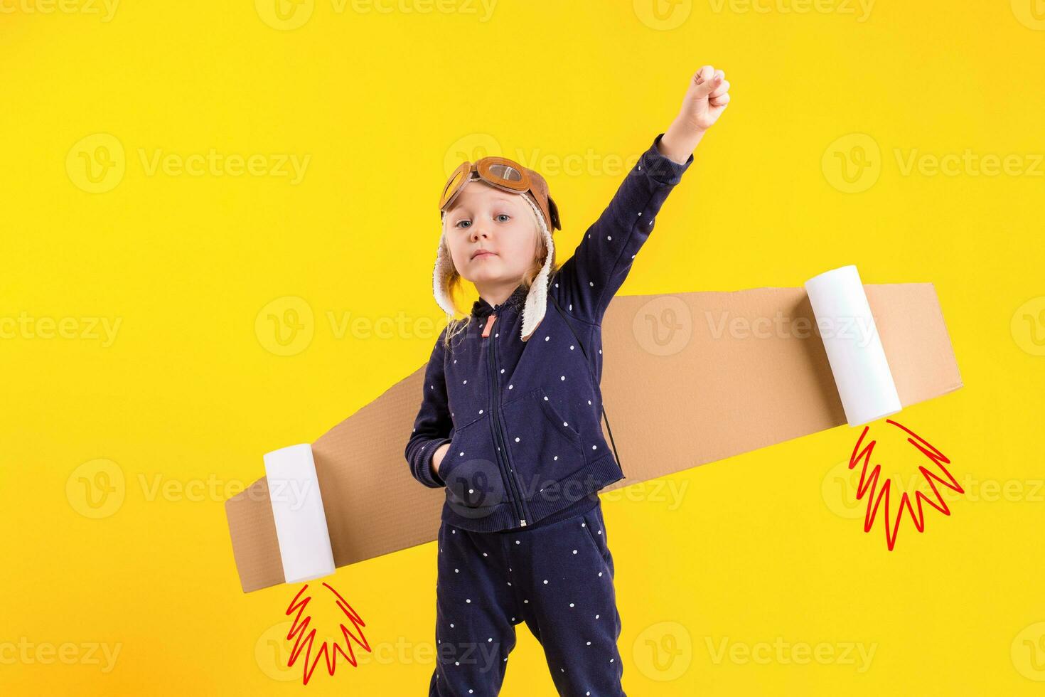 Freedom, girl playing to be airplane pilot, funny little girl with aviator cap and glasses, carries wings made of brown cardboard as an airplane photo