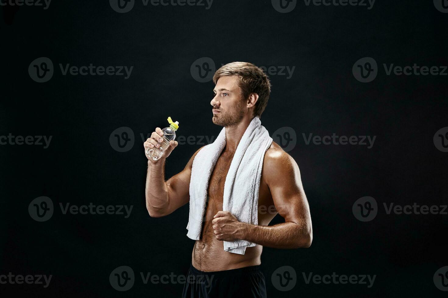 Portrait of a fitness man with towel on shoulders looking away. Happy young man relaxing after training. photo