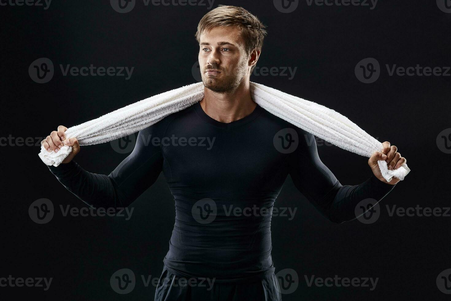 Portrait of a fitness man with towel on shoulders looking away. Happy young man relaxing after training. photo