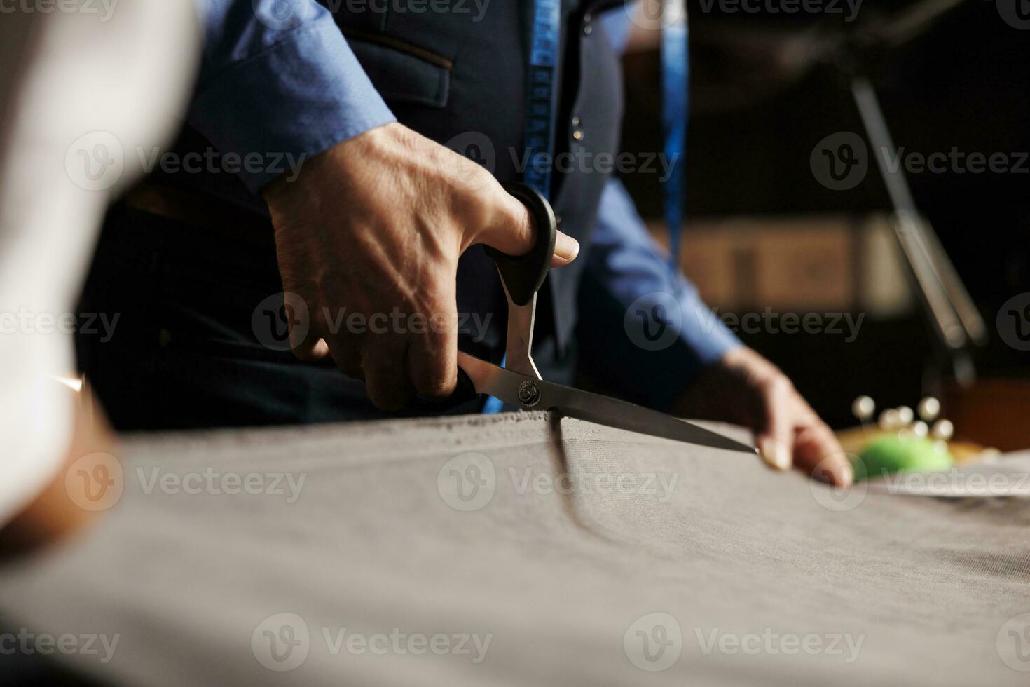 Fashion industry specialists manufacturing suit in atelier workspace, cutting textile material with scissors for upcoming bespoke collection. Process of making clothes in luxury tailoring studio photo