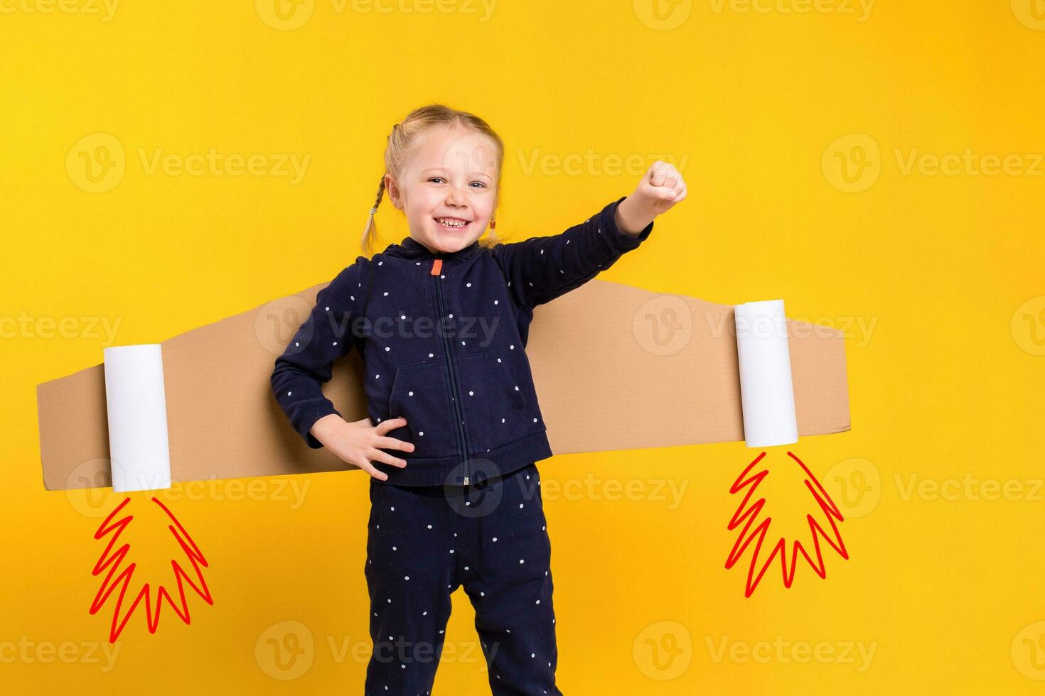A little child girl is wearing homemade cardboard flying wings, pretending to be a pilot for a craft, imagination or exploration concept. photo