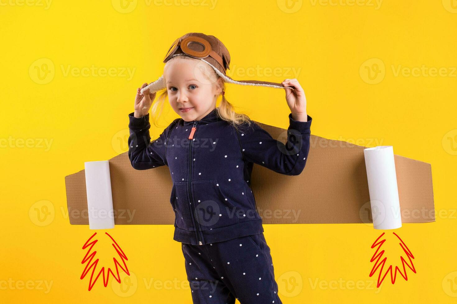 libertad, niña jugando a ser avión piloto, gracioso pequeño niña con aviador gorra y anteojos, lleva alas hecho de marrón cartulina como un avión foto