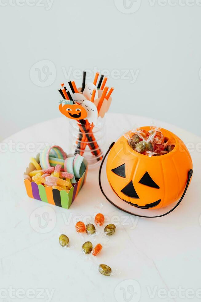 Halloween candies in orange pumpkin bucket with candy on white background photo