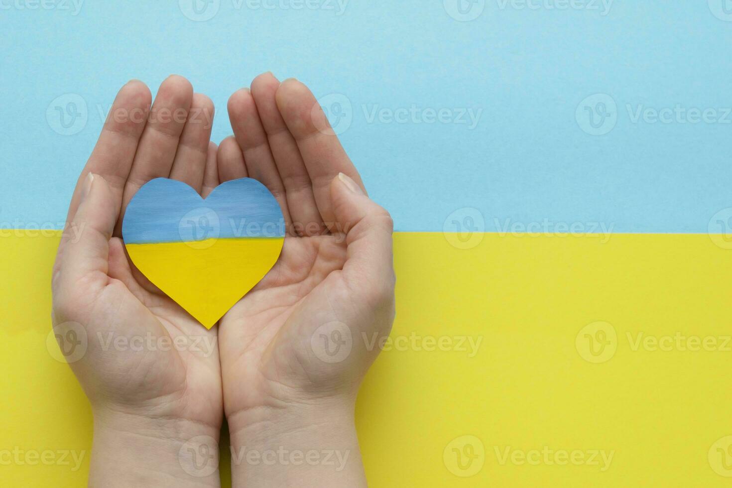 The concept of ending the war in Ukraine. heart in the colors of the flag of Ukraine in female hands. photo