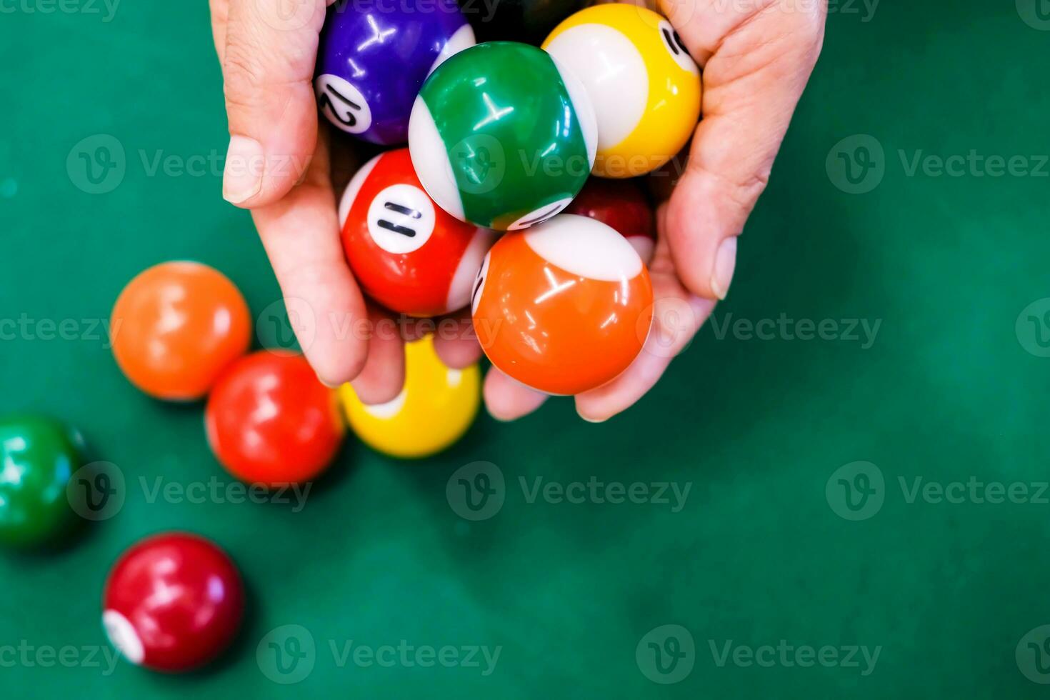 Hand holding colorful billiard ball sphere on green flannel on snooker table, snooker is photo