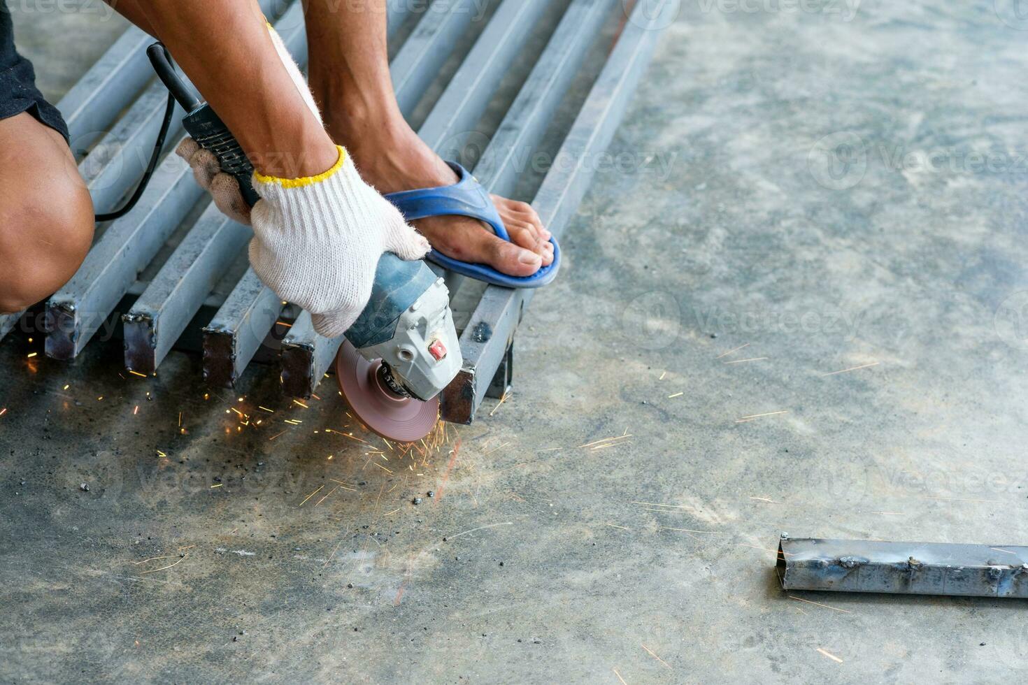 Worker cutting metal with grinder with sparks photo
