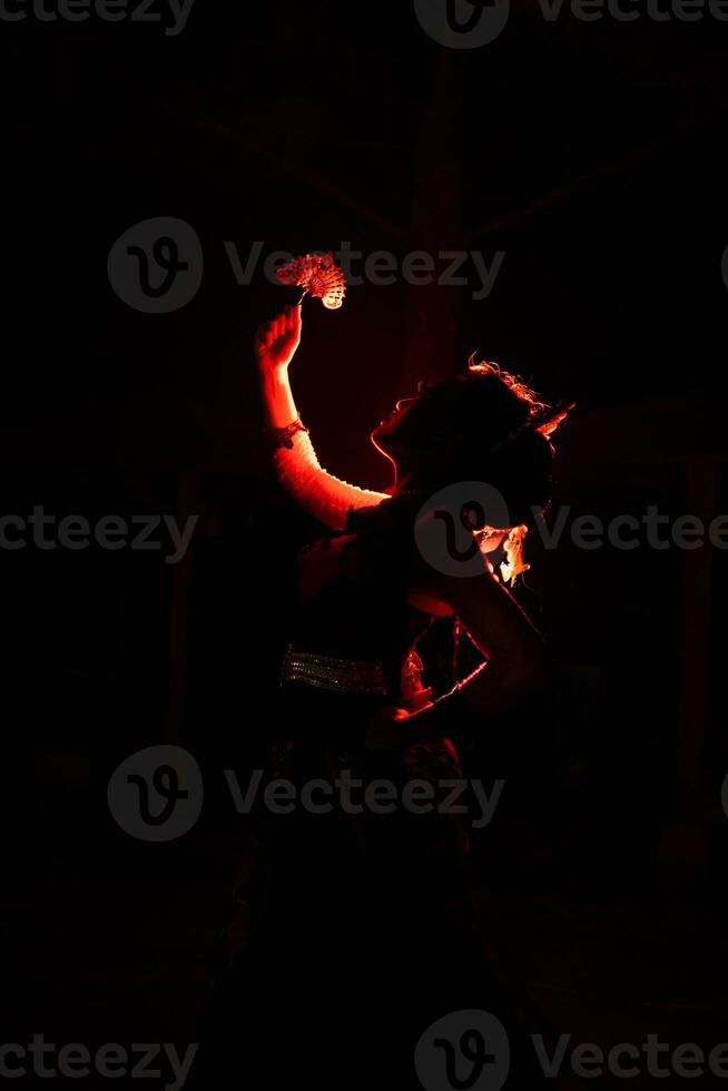 the silhouette of a female dancer holding jewelry that looks like a reflection reflecting in the dim light photo