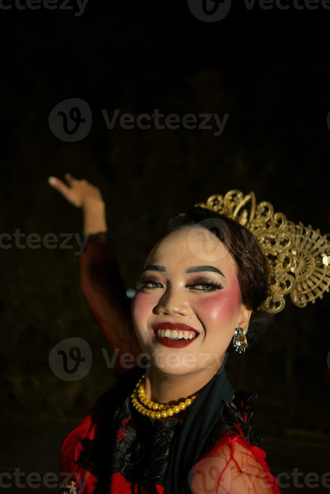 an Asian woman with makeup on her face and wearing a black shawl while dancing photo