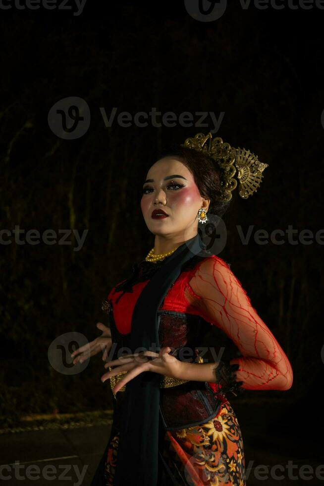 un asiático mujer con maquillaje en su cara y vistiendo un negro chal mientras bailando foto