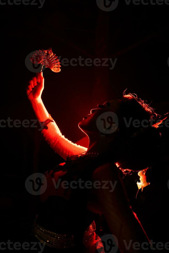 silhouette of a female dancer holding jewelry in the middle of the stillness of the night with red light photo